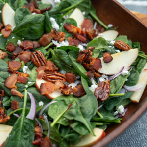 Spinach salad topped with apples, Fletcher's bacon, goat cheese and candied pecans. Served in a large wood salad bowl.